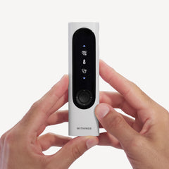 Withings BeamO — Beam-O — Vorderansicht in zwei Händen gehalten, schwarzes Display mit medizinischen Symbolen und Drehknopf, weißes Gehäuse auf einfachem Hintergrund — in der Hand gehalten, Vorderseite, Nahaufnahme, weiß