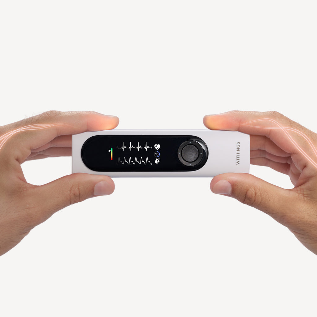 Withings BeamO — Beam-O — Gerät wird horizontal mit beiden Händen gehalten, EKG-Bildschirm leuchtet, weißer Hintergrund, stilisiertes Licht auf den Fingern — zwei Hände, aktiver Bildschirm, handgeführt