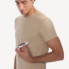 Withings BeamO — Beam-O — Mann im beigen T-Shirt hält das weiße BeamO-Gerät in der Hand, Dreiviertelperspektive, schlichter weißer Hintergrund — Freizeitkleidung, handgehalten, neutraler Hintergrund