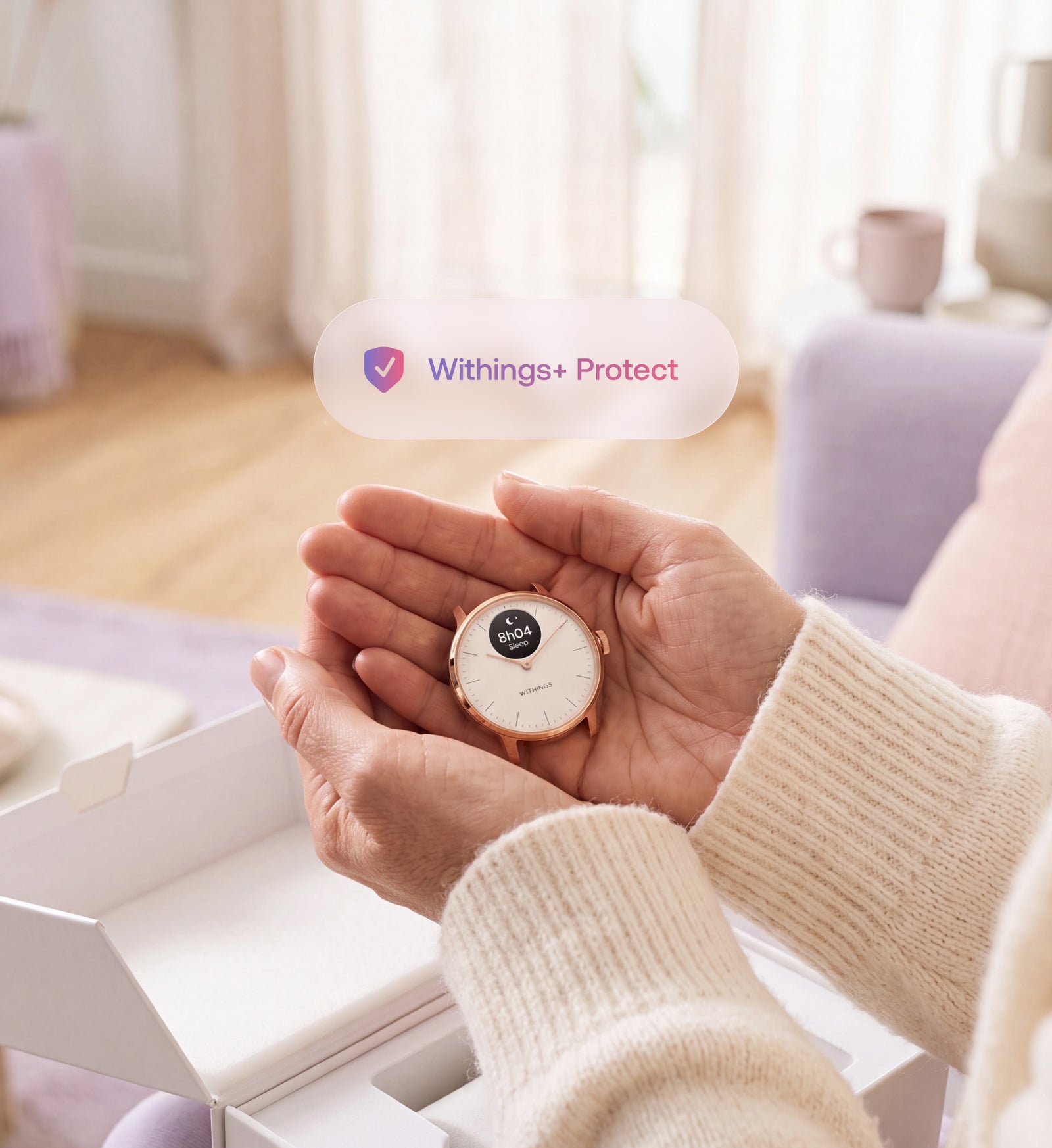 Withings+ Protect — ScanWatch Light — Hands holding the watch out of its box, floating Withings+ Protect badge, bright indoor setting — unboxing, rose gold, close-up