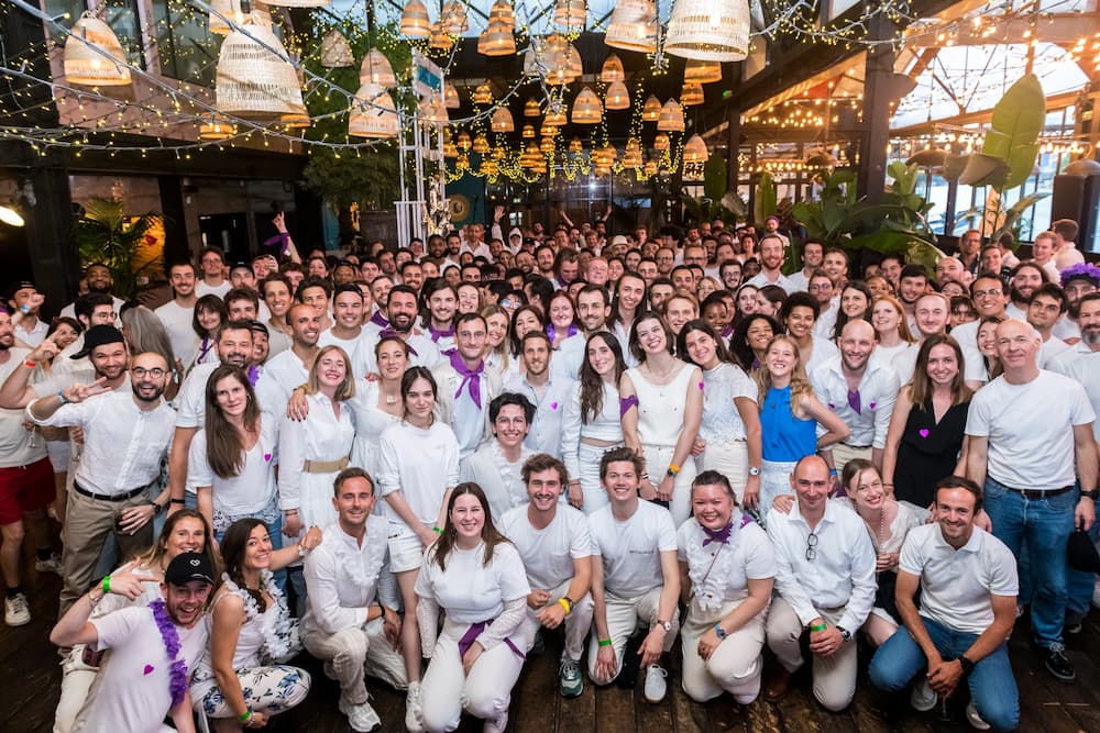 Withings — Team — Large group photo in white outfits with purple accessories at an indoor festive company event — corporate event, group, white and purple