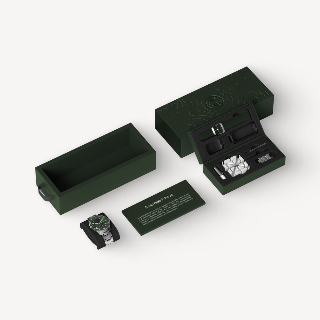 ScanWatch Nova — Verde 42mm — Unboxing completo: caja verde oscura abierta con reloj, correa, accesorios y tarjeta del producto sobre fondo gris claro — embalaje, unboxing, vista isométrica, caja verde