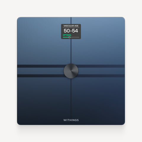 Withings Body Comp — Black — Top-down view on neutral background, screen displaying vascular age 50-54 optimal, dark blue surface — top-down, neutral background, lit display, midnight blue