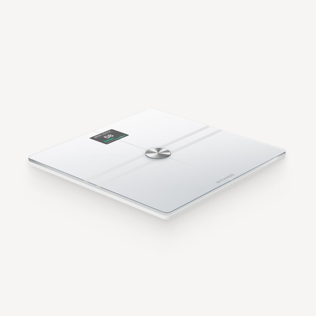 Withings Body Comp — White — Three-quarter perspective view on white background, OLED screen lit, brushed chrome center button — three-quarter, neutral background, white, lit screen