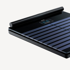 Body Scan — Black — Three-quarter top-down view, black and blue striped surface with illuminated ECG screen, neutral background — close-up, three-quarter, ECG display, dark