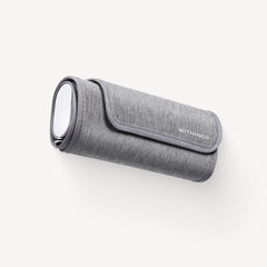 Withings BPM Connect — Verbundene Blutdruckmanschette — Dreiviertelansicht auf weißem Hintergrund, aufgerollte Manschette mit ovalem Silberdisplay und Withings-Logo — grau, kompakt, Stoff