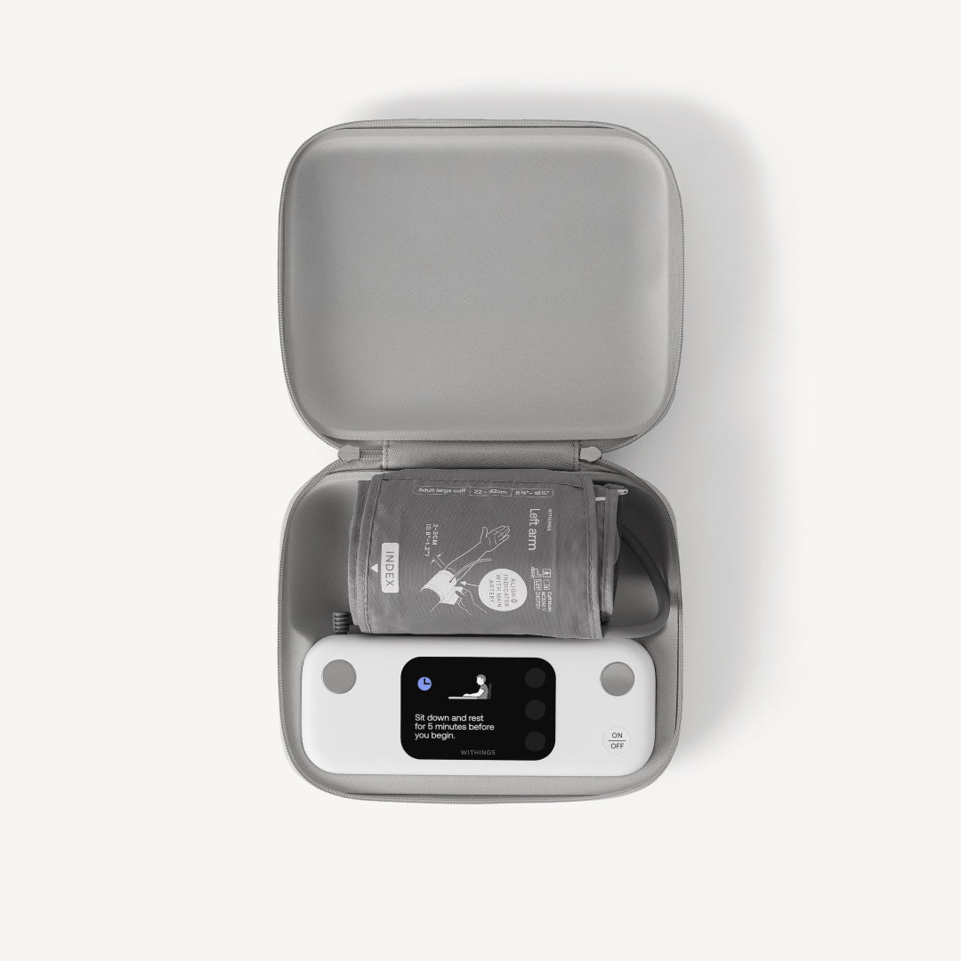 BPM Vision — Connected blood pressure monitor — Top-down view of device and adult large cuff stored in open grey travel case, white background — top-down, case, cuff, screen on