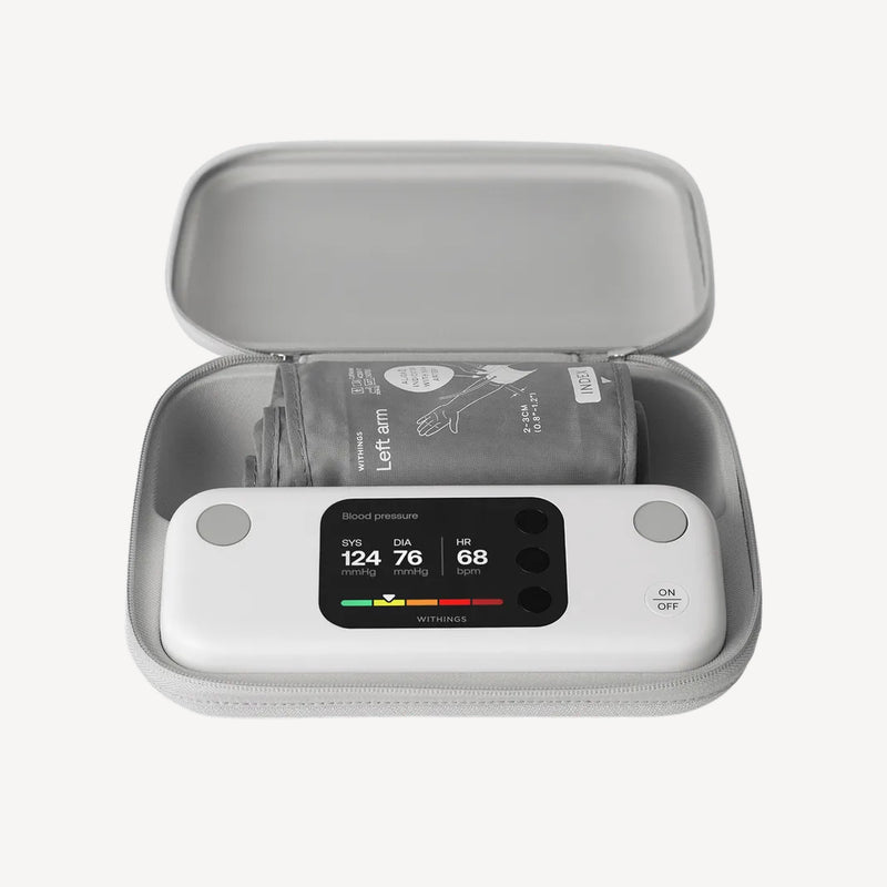 BPM Vision — Connected Blood Pressure Monitor — Top-down view in open grey travel case, screen showing SYS 124 DIA 76 HR 68, cuff folded inside — travel case, lit display, top-down, open case